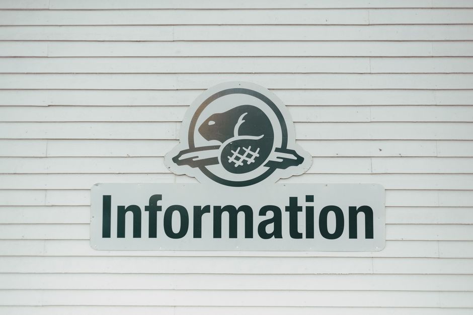 Close-up of an information sign on a textured white wall, featuring a beaver logo.